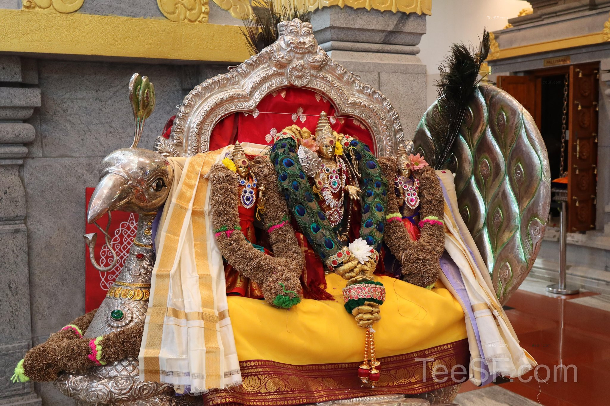 A richly decorated deity figure seated with red and gold fabric.
